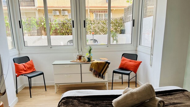 Une chambre avec un lit, deux chaises, une petite table avec des boissons et une vue sur le balcon extérieur.
