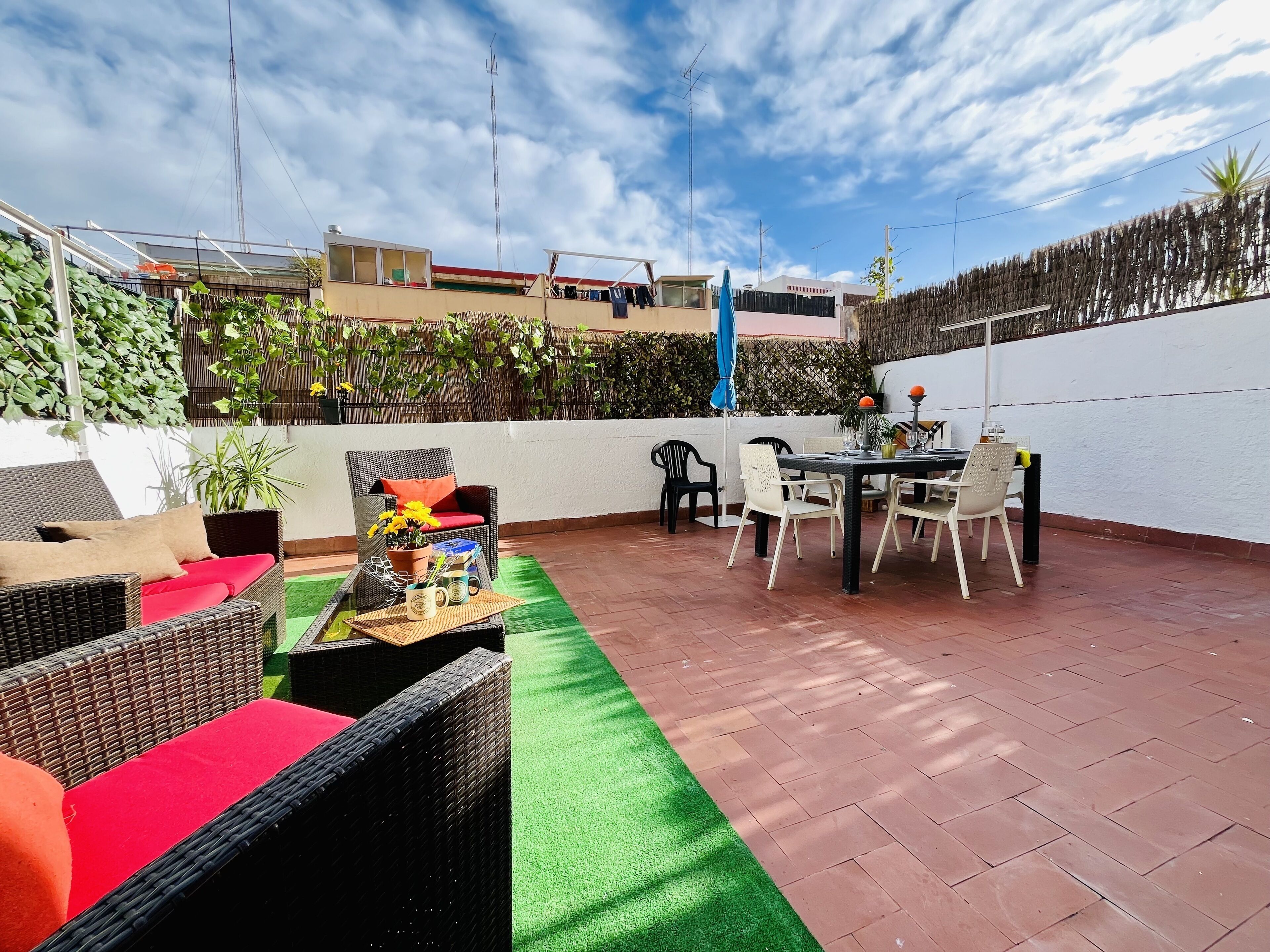 Eine Terrasse mit Korbmöbeln, einem Esstisch und Stühlen.