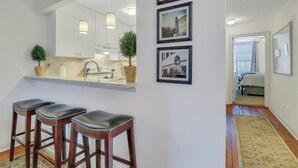 Une cuisine moderne avec des meubles blancs, une cuisinière encastrée et un coin bar avec des tabourets.