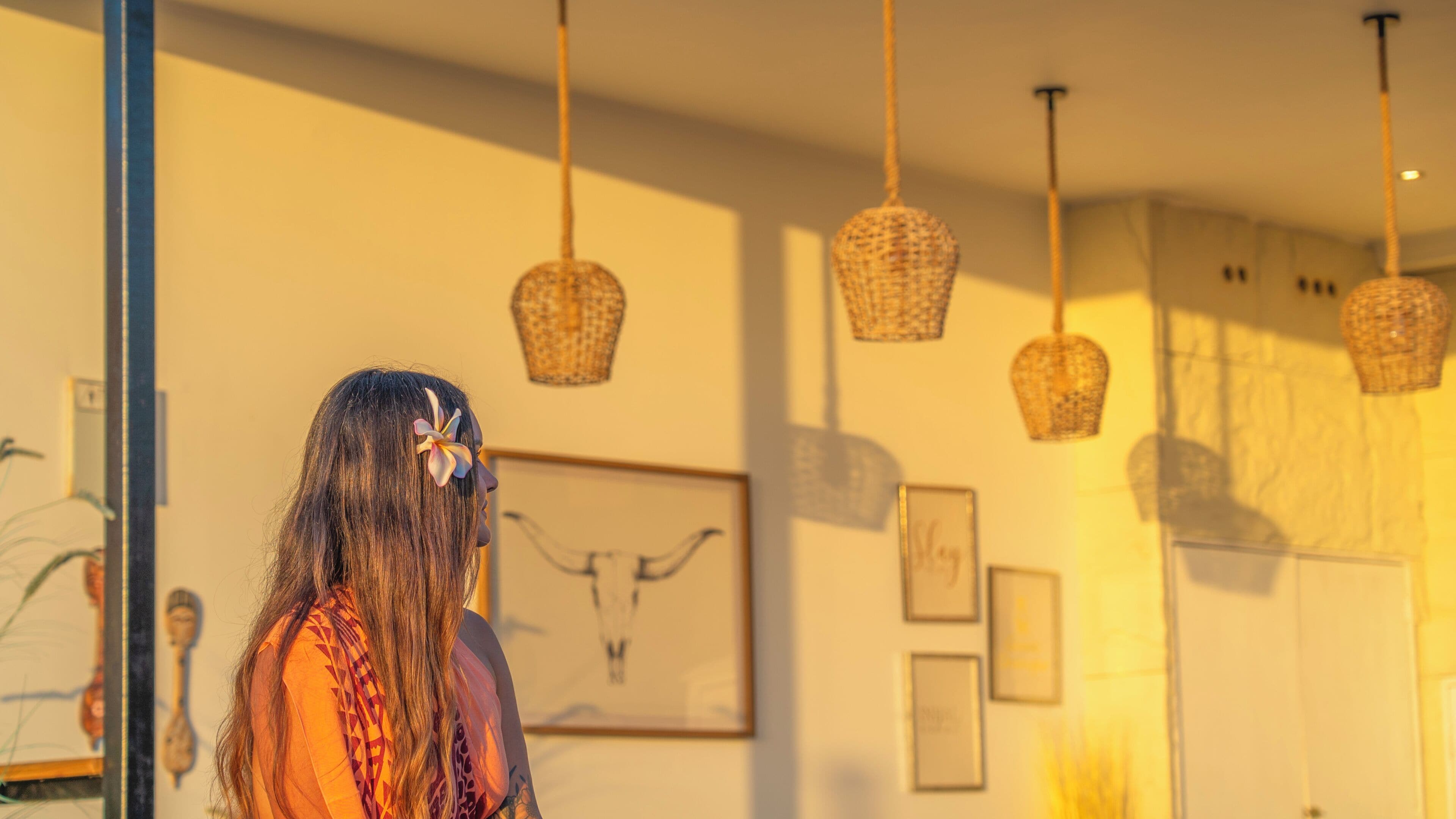 A person standing in a room with hanging baskets and framed artwork on the walls.