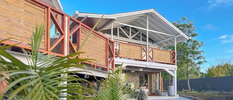 A modern house with a wooden exterior, a balcony, and a stone pathway leading to the entrance.
