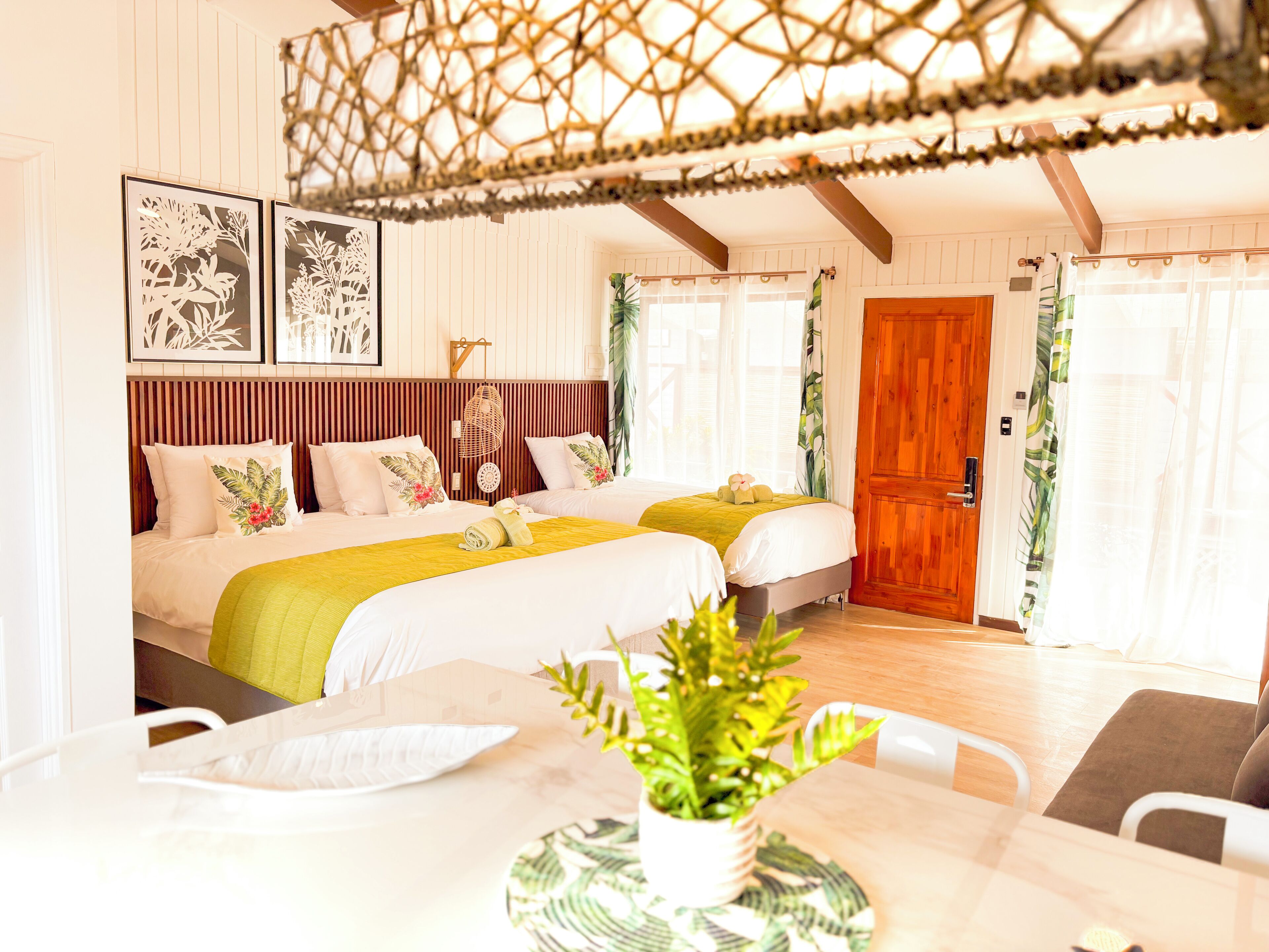 Een hotelkamer met twee bedden, een houten deur en een zithoek met een tafel en stoelen.