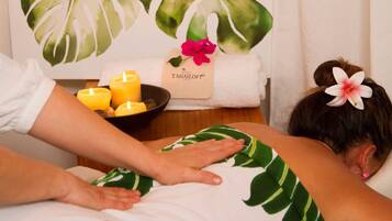 A massage therapy session in a spa setting with a tropical-themed room.