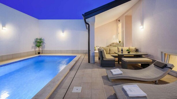 A pool area with a lounge chair, a table, and a sofa.
