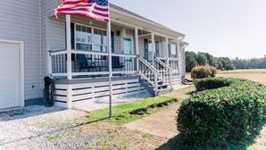 Ein zweistöckiges Haus mit Veranda, Fahnenmast mit amerikanischer Flagge und gepflegtem Rasen.