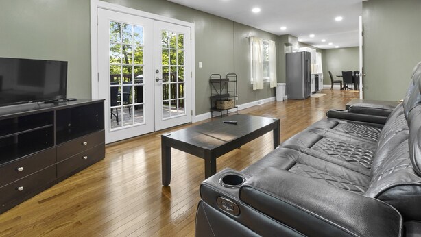 Una sala moderna con un sofá de cuero, un televisor y un comedor con una mesa y sillas.