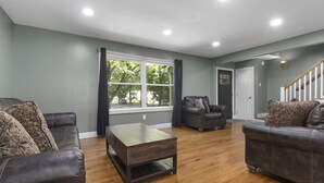 Una sala de estar con dos sofás de cuero, una mesa de centro de madera y un sillón oscuro.