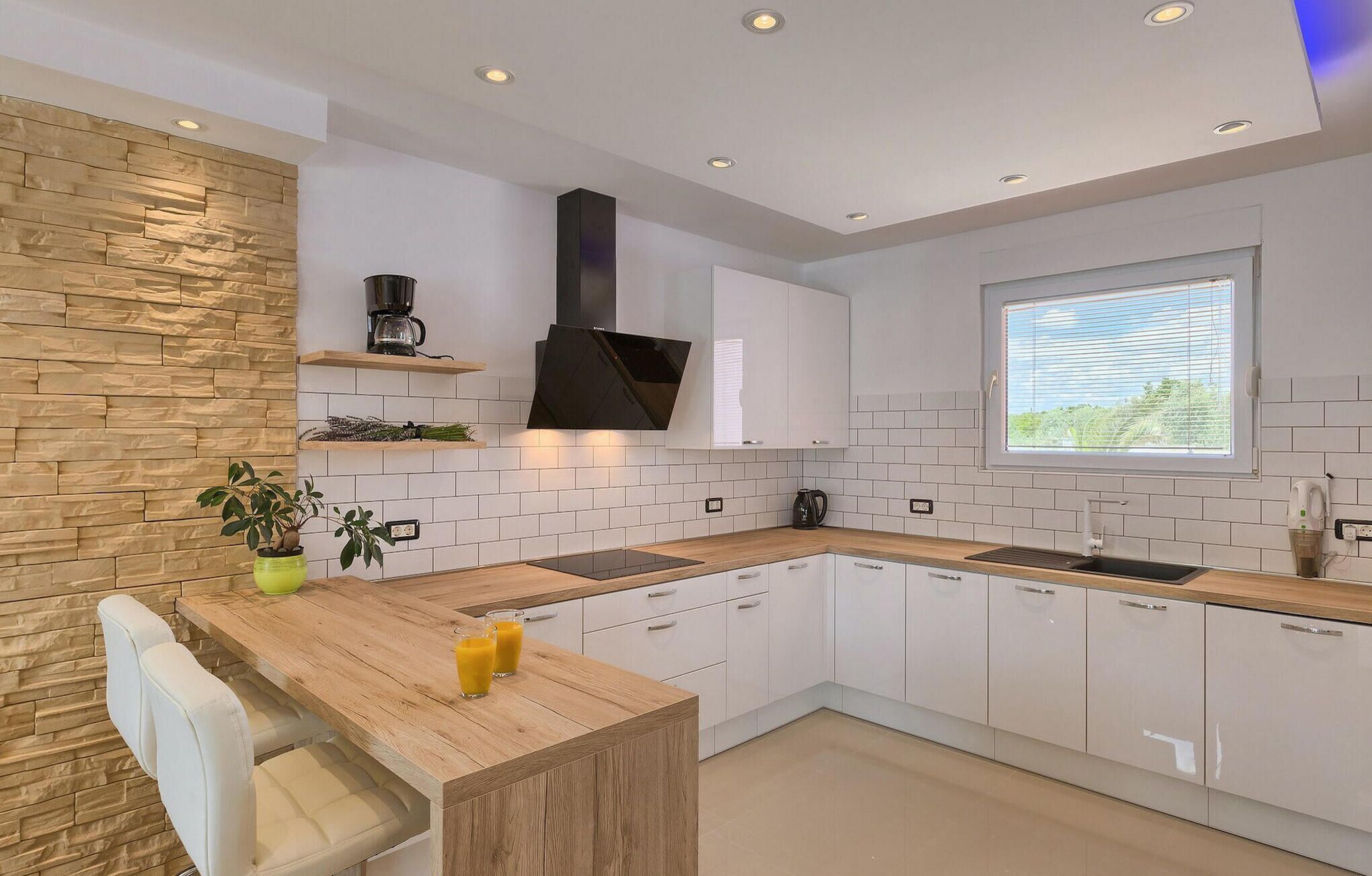 Una cocina moderna con gabinetes blancos, una encimera de madera y una estufa integrada.