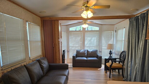 A spacious living area with a sofa, a dining table, and a ceiling fan.
