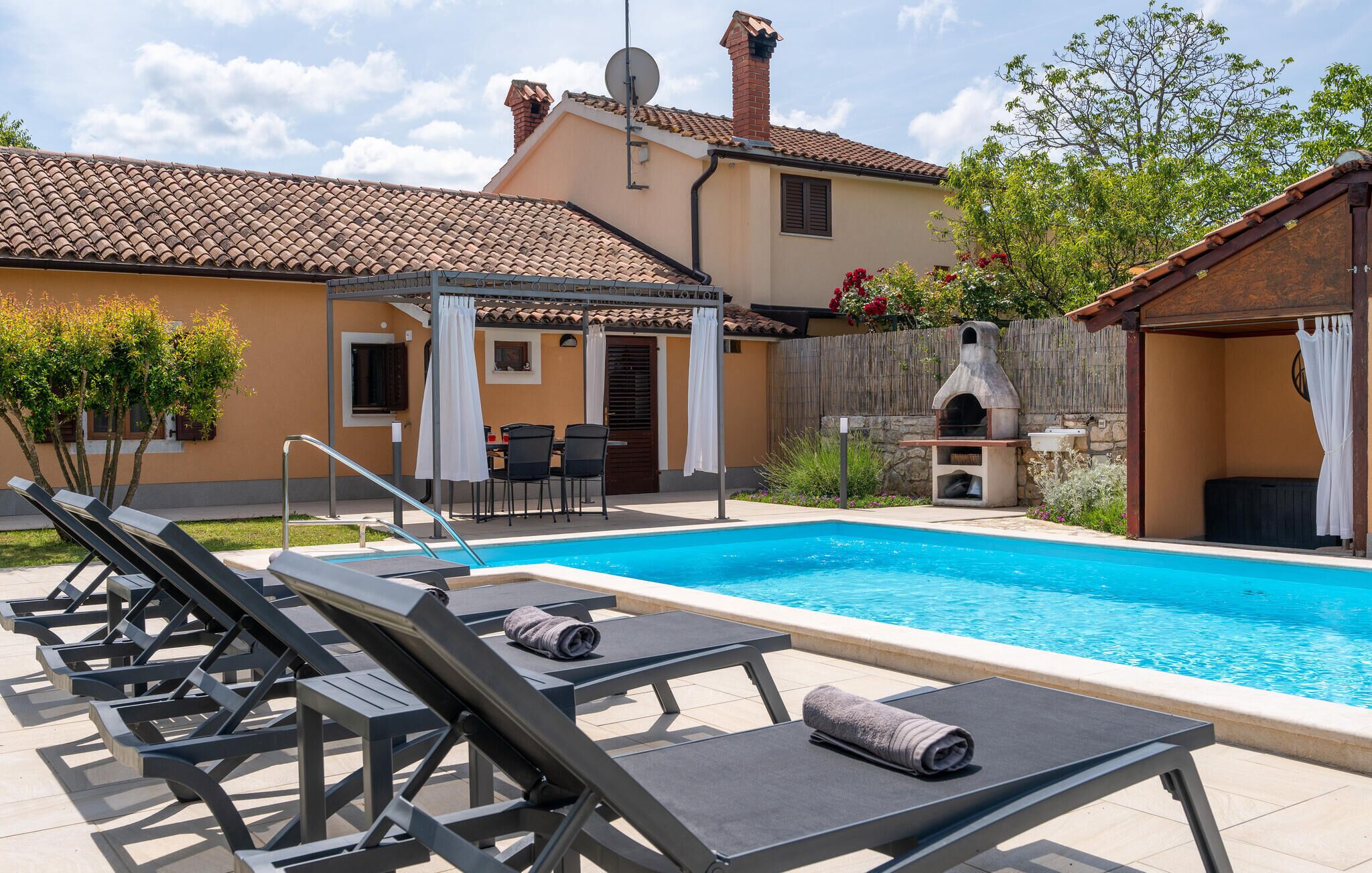A swimming pool with lounge chairs, a barbecue area, and a covered patio.