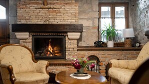 A cozy living room with a stone fireplace, two armchairs, a round coffee table, and a potted plant. - Lovely home in Krsan with WiFi (Krsan)