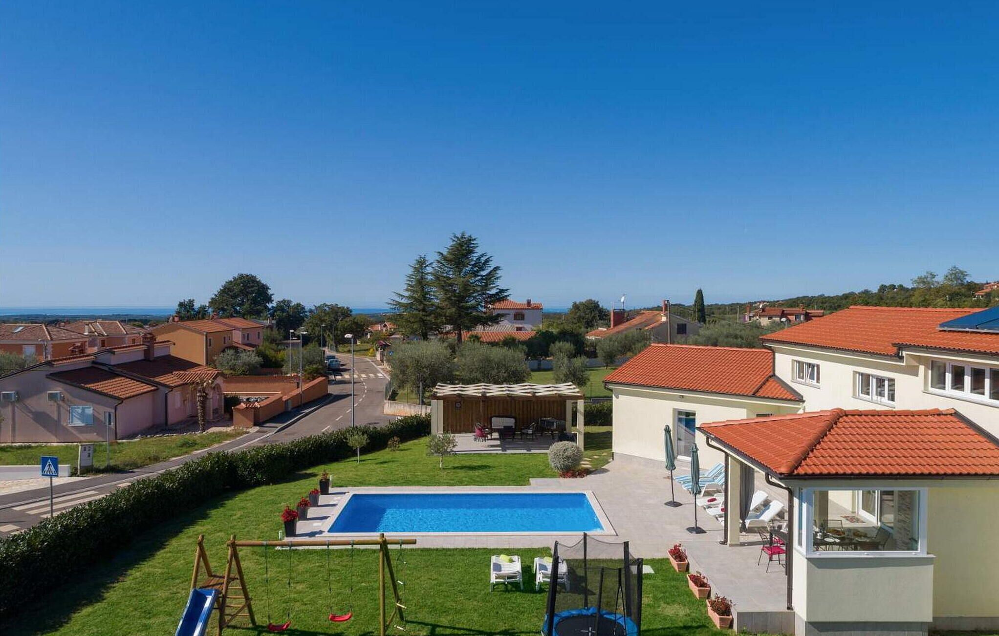 Zona residencial com piscina, área de estar externa e vista para o mar.