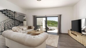 A modern living room with a sofa, coffee table, TV, and a staircase. - Amazing home in Martina with sauna (Martina)