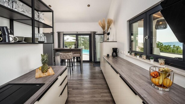 A modern kitchen with a view of a pool, wooden ceiling beams, and a dining area with a view. - Amazing home in Martina with sauna (Martina)