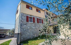 Stunning Mediterranean-style building with a two-story facade, red shutters, and a charming garden.