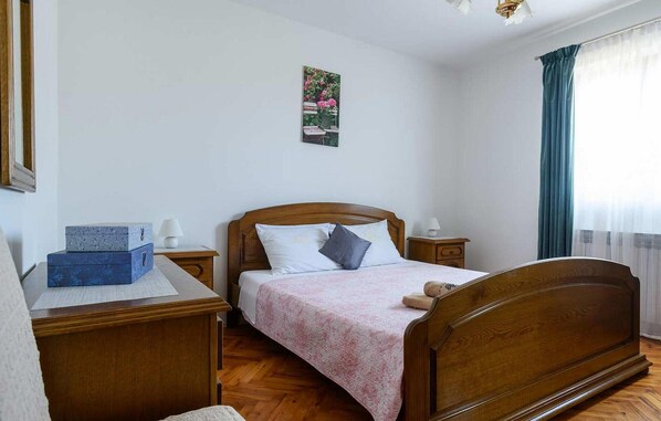 A neatly arranged bedroom with a wooden bed, a bedside table with a lamp, and a small desk with a lamp. - Gorgeous home in Rovinj with WiFi (Rovinj)