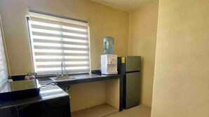 Eine kleine Küche mit einem Kühlschrank, einem Wasserspender und einem Spülbecken.