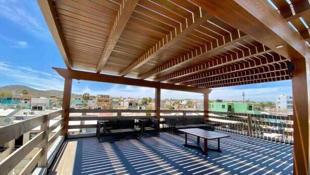 Eine Terrasse im Freien mit einer Holz-Pergola, Tischen und Stühlen.