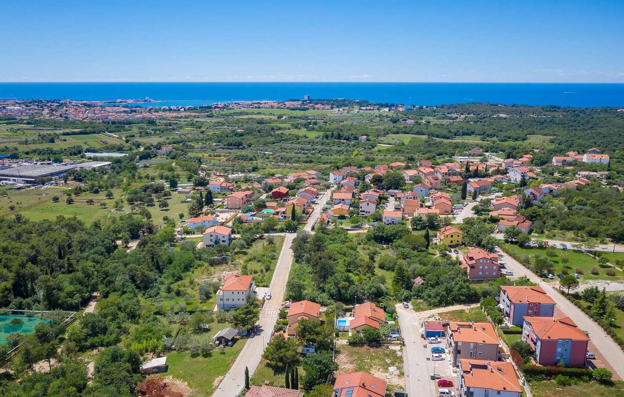 Vista aérea de una zona residencial costera con casas, carreteras y una gran masa de agua al fondo.