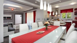 A modern dining area with a glass table, red runner, white chairs, and a vase of flowers. - Lovely home in Motovun with WiFi (Motovun)