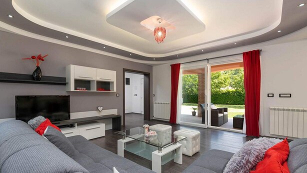 A modern living room with a sofa, coffee table, and TV. There is a sliding glass door leading to an outdoor area with furniture. - Lovely home in Motovun with WiFi (Motovun)