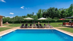 A swimming pool with lounge chairs and umbrellas, surrounded by a grassy area and trees. - Lovely home in Motovun with WiFi (Motovun)