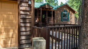 A wooden cabin with a porch, a garage, and a deck.