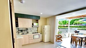 Una cucina moderna con mobili chiari in legno, forno a microonde integrato e frigorifero bianco.