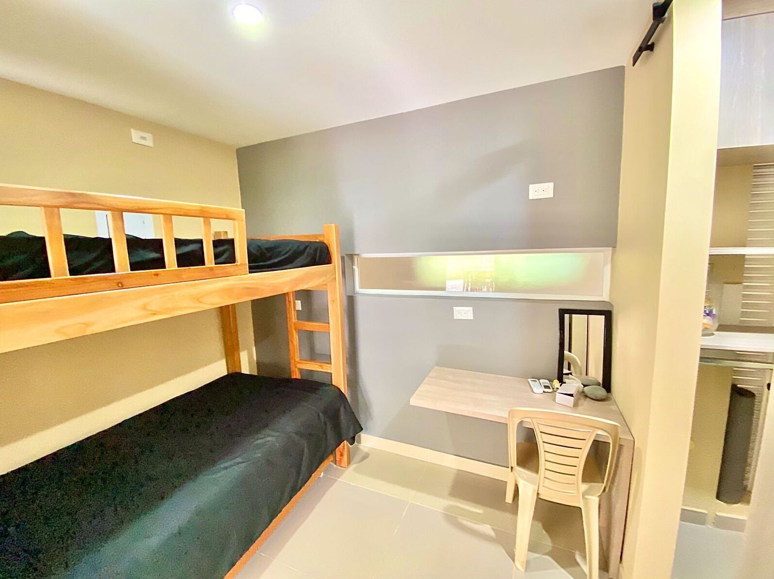 A compact room with a bunk bed, a desk, and a chair.