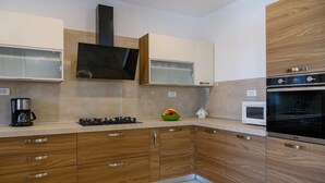 Una cocina moderna con armarios de madera, estufa a gas, microondas y un televisor grande.