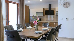 Un comedor con una mesa de madera dispuesta para seis personas, seis sillas y un florero con flores.