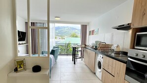 Una cocina moderna con lavadora, zona de comedor con vistas y balcón con cortinas.