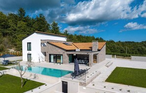 Ein modernes, zweistöckiges Haus mit Swimmingpool, Außenbereich und Blick auf die umliegende Natur.