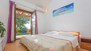 A bedroom with a bed, a nightstand, a window with curtains, and a painting on the wall. - Beautiful home in Porec (Porec)