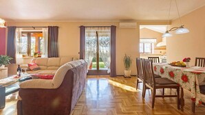 A living room with a sofa, a dining table with chairs, and a kitchen in the background. - Beautiful home in Porec (Porec)