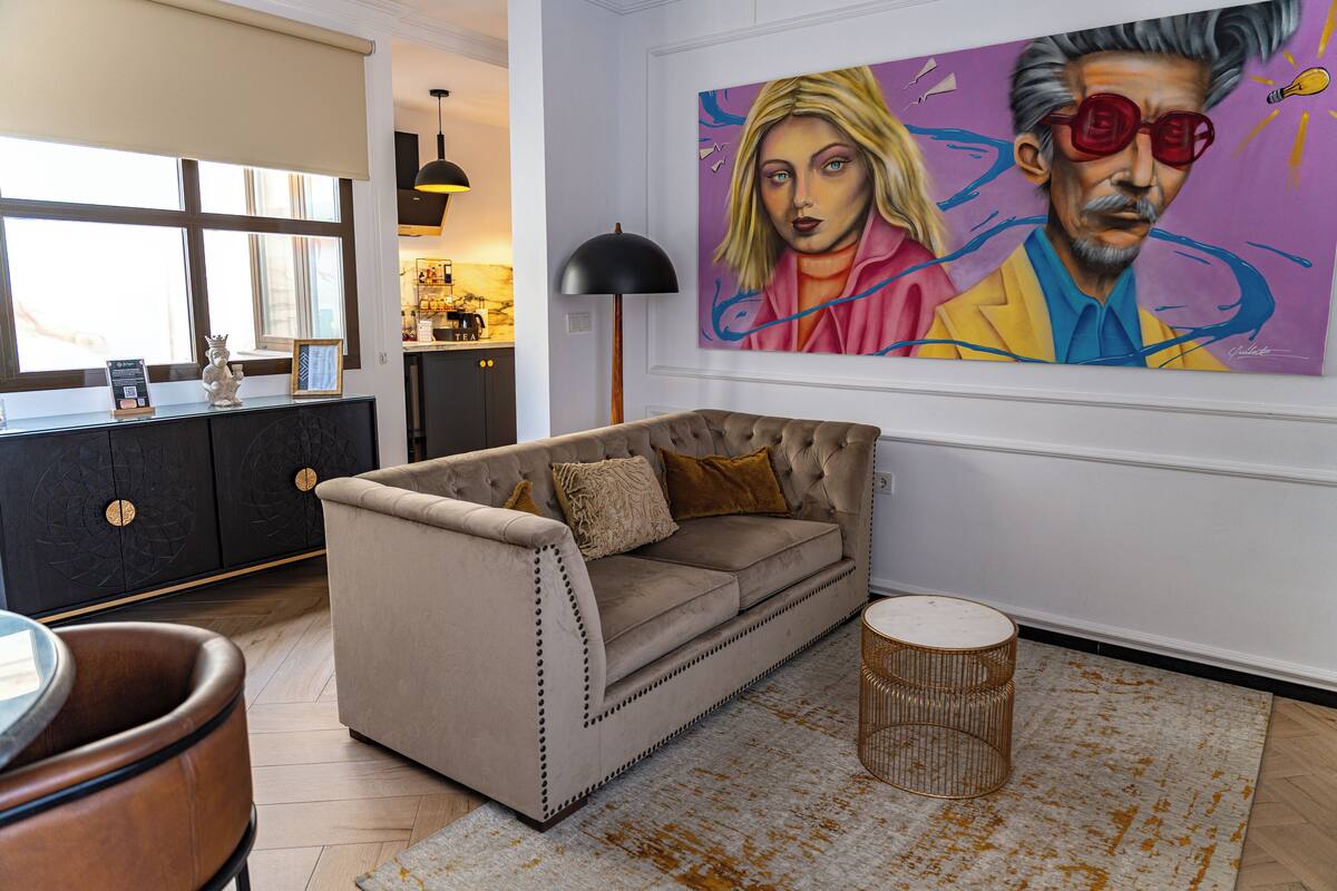 A living room with a beige sofa, a round coffee table, and a large abstract painting on the wall.