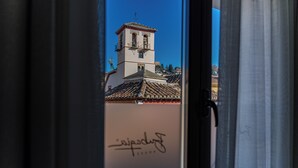 Blick durch ein Fenster, mit dem Kirchturm eines Gebäudes und einer handschriftlichen Signatur auf dem Glas.