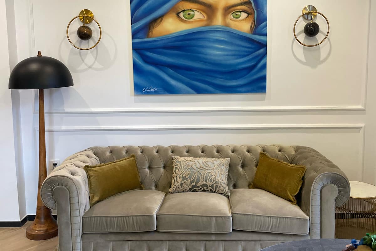 A living room with a tufted sofa, a round coffee table, and a painting on the wall.