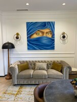 A living room with a tufted sofa, a round coffee table, and a painting on the wall.