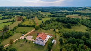 A white house with a red roof surrounded by green fields and trees.