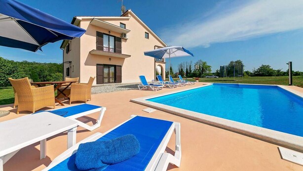 A modern two-story house with a swimming pool, outdoor seating, and a well-maintained lawn.