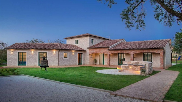 A two-story house with a stone facade, a patio with a fire pit, and a well-maintained lawn. - Beautiful home in Vodnjan (Vodnjan)