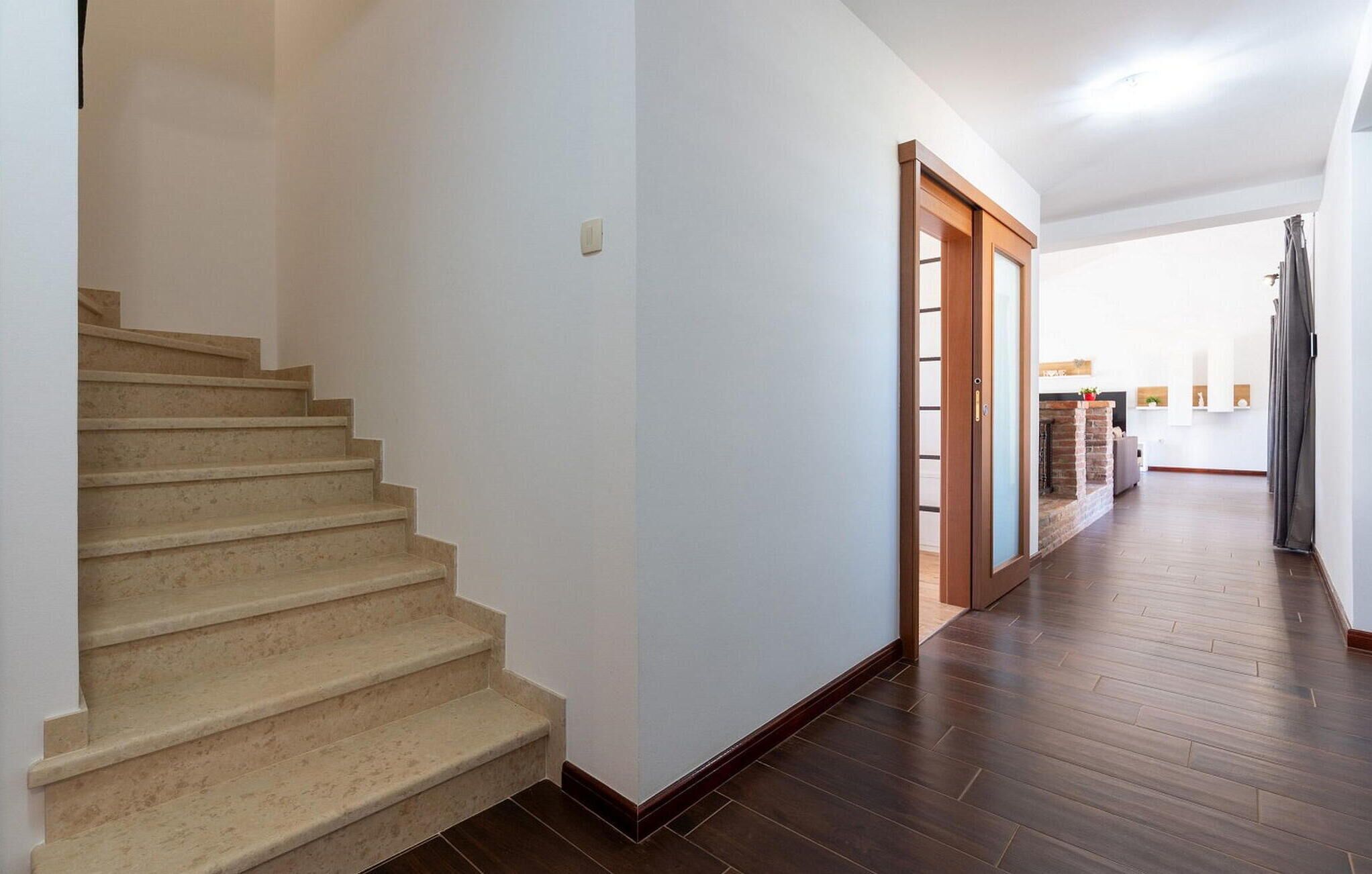 A hallway with a wooden staircase, a door with a glass panel, and a brick fireplace.
