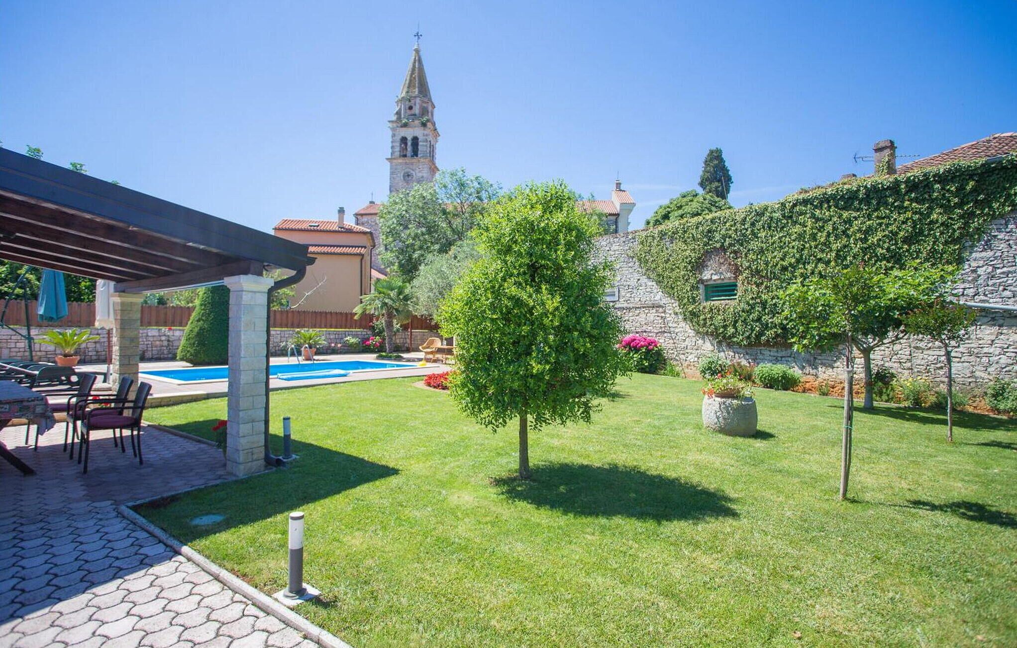 Un jardin avec une piscine, une pergola et un mur en pierre.