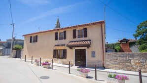 Un bâtiment à deux étages, doté d’un toit en tuiles, d’une petite tour et d’un mur en pierre.