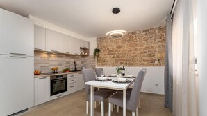 Een moderne keuken met witte kasten, een stenen muur en een eetgedeelte met een tafel voor vier personen.