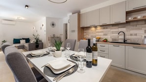 Een moderne keuken met witte kasten, een houten aanrechtblad en een eethoek voor vier personen, gedekt voor een maaltijd.