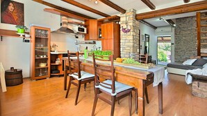 Une cuisine spacieuse avec des meubles de rangement en bois, une table à manger avec des chaises et un mur en pierre.