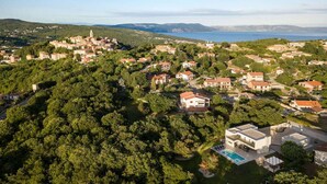 Oversigtsbillede af en kystlandsby med traditionelle huse, en markant kirke og et stort vandområde i baggrunden.