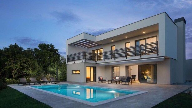 Et moderne hus med to etager, swimmingpool, udendørs møbler og en balkon.